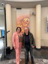 Two visitors with a programme in front of the coral work, between two columns of the foyer.