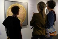 Three visitors in front of the peach planet, one of them reading the poem beside it.