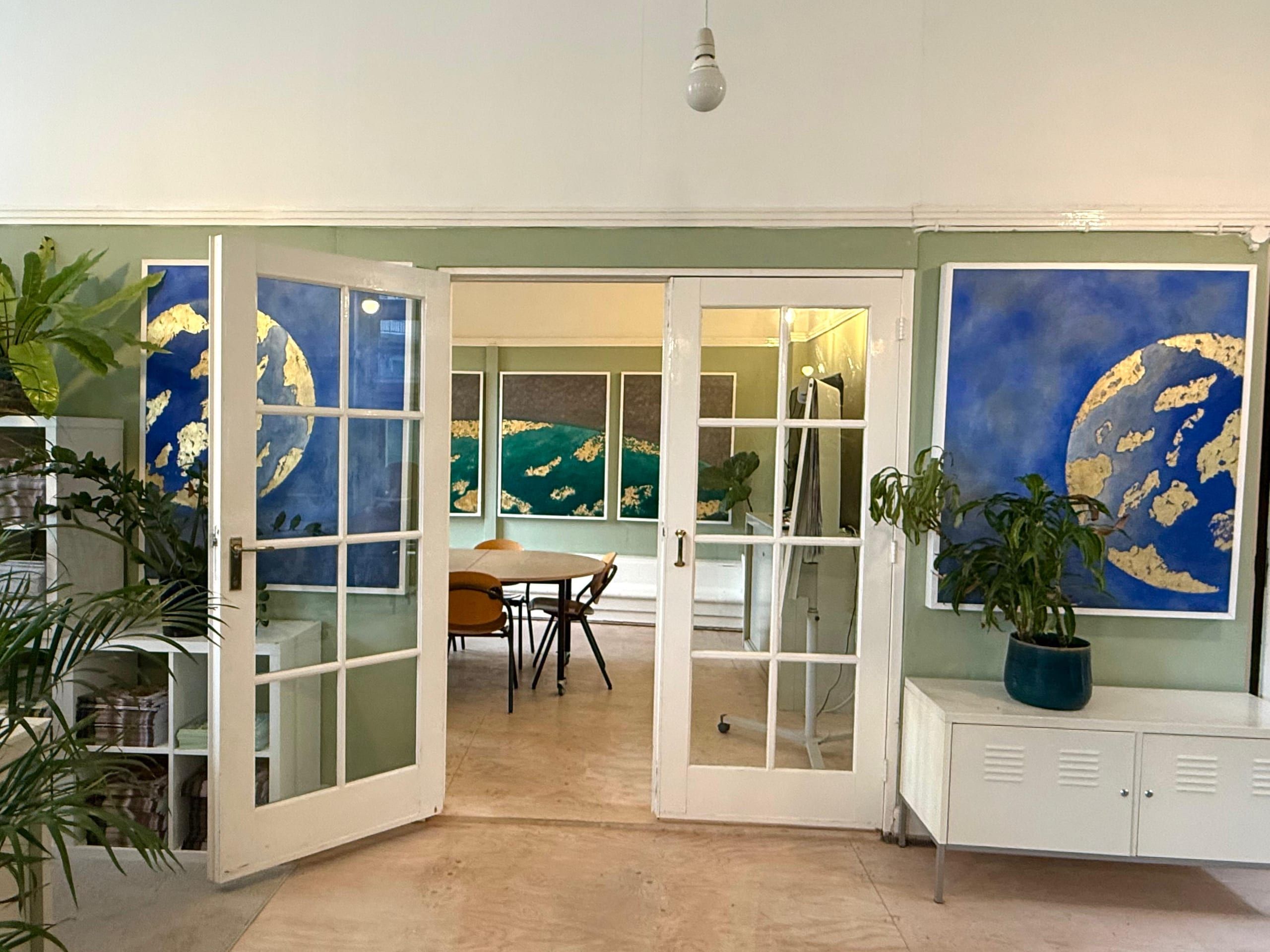 Blue and gold planetary paintings either side of an open doorway, looking through to the meeting room.