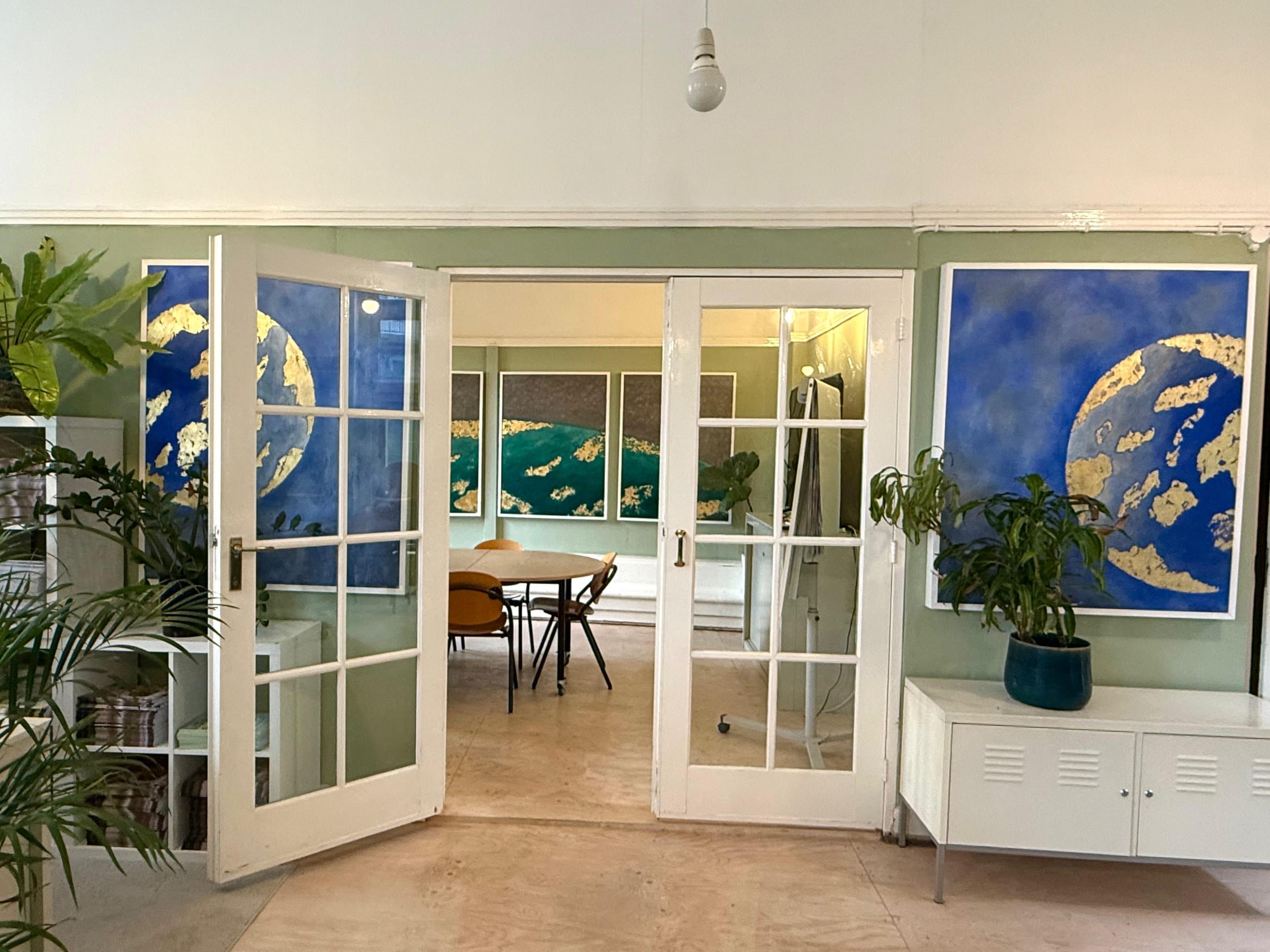 Blue and gold planetary paintings either side of an open doorway, looking through to the meeting room.