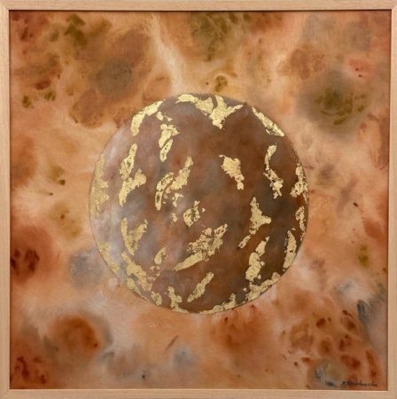 A brown planet with islands of gold-coloured metal leaf against an ochre and rust sky, in a light wooden frame.