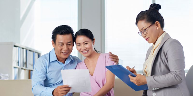 Asian couple going over MRP certification with VA Loan specialist.