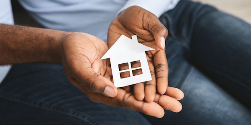 Hands holding a small house model.
