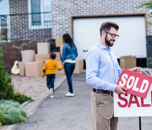 Man placing sold sign to house listing.