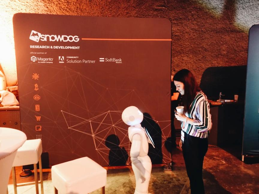 A woman is looking at the tablet visible on Pepper's chest. The robot is looking up at her face. They are interacting. It looks like a conversation.