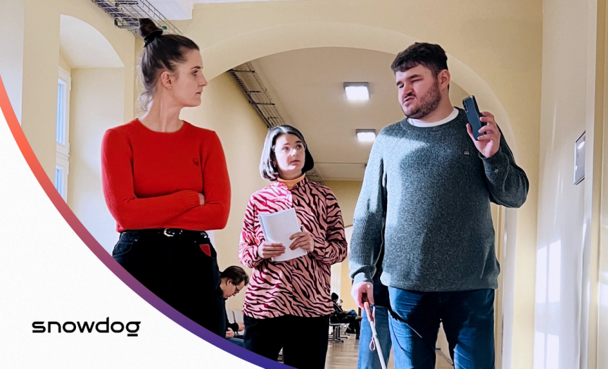 The photo shows 3 people: a blind tester who conducts usability testing of the mobile app and 2 female specialists who conduct the test. They talk.