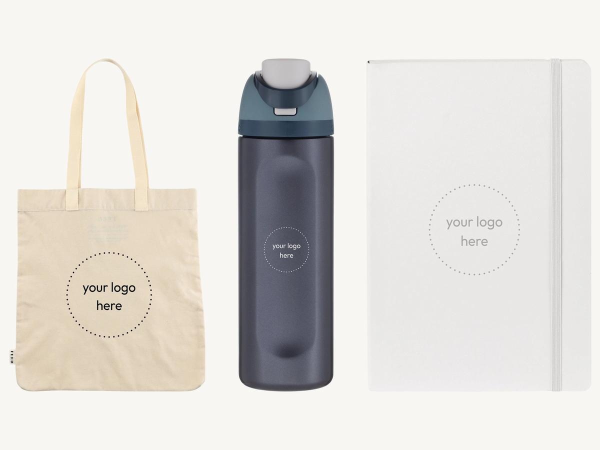 A branded organic cotton convention tote, an insulated water bottle and a softcover notebook on a cream background, each marked for a logo.