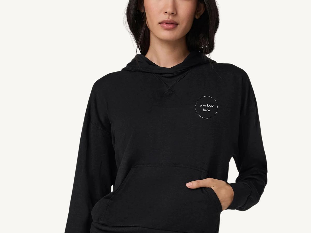 Vuori Women's Halo Modern Pullover Hoodie on a cream background, ready for an embroidered company logo.