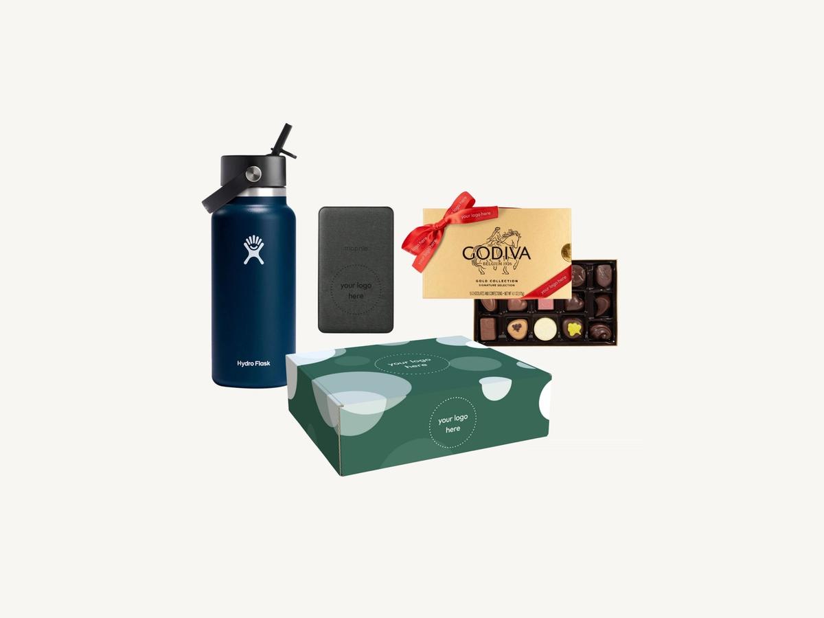 A premium branded gift pack on a cream background with a bottle, a power bank and gold-boxed chocolates.