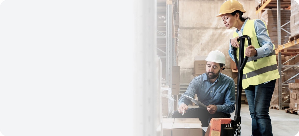 Dvaja pracovníci s prilbou kontrolujúci zásielky a tovar v sklade – ilustrácia implementácie Digital Product Passport v logistike.