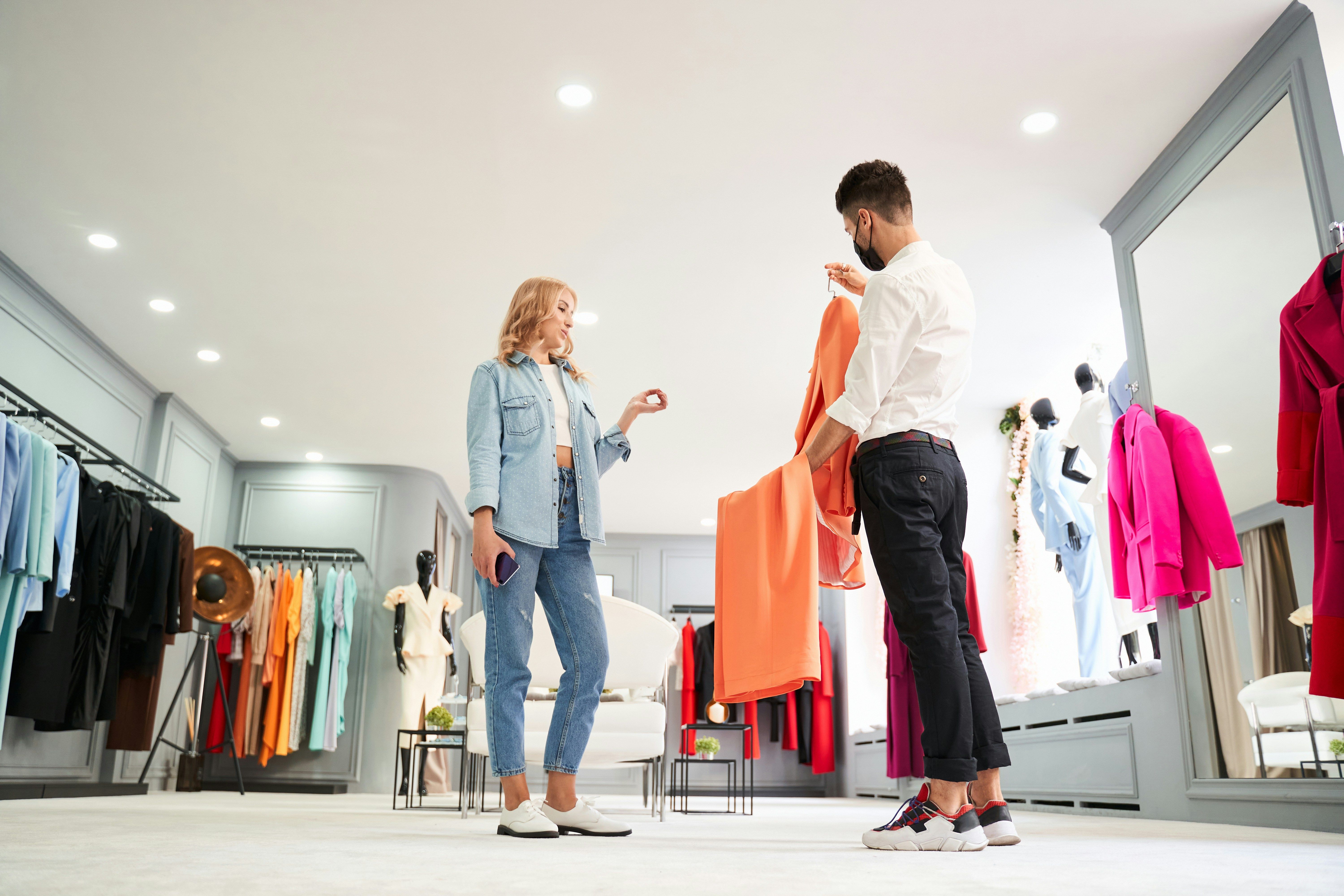 Продавач консултант в магазин обяснява как работят дигиталните продуктови паспорти за текстил