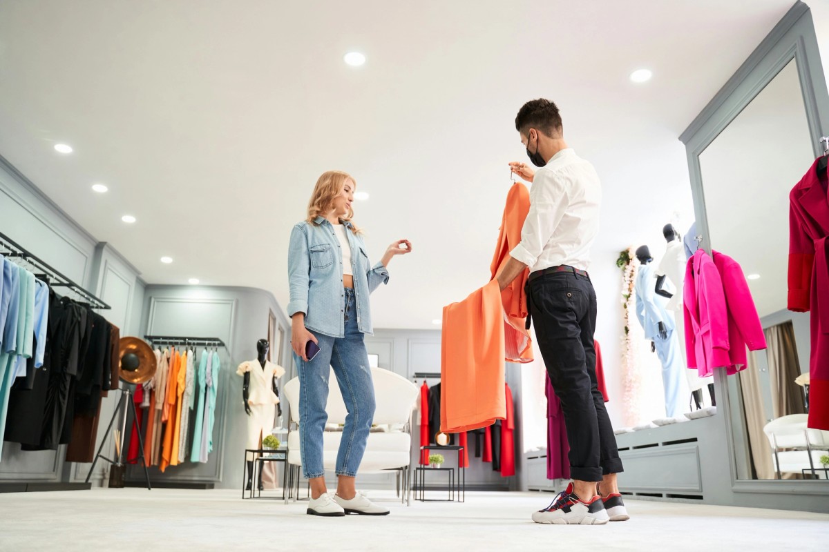 Продавач консултант в магазин обяснява как работят дигиталните продуктови паспорти за текстил