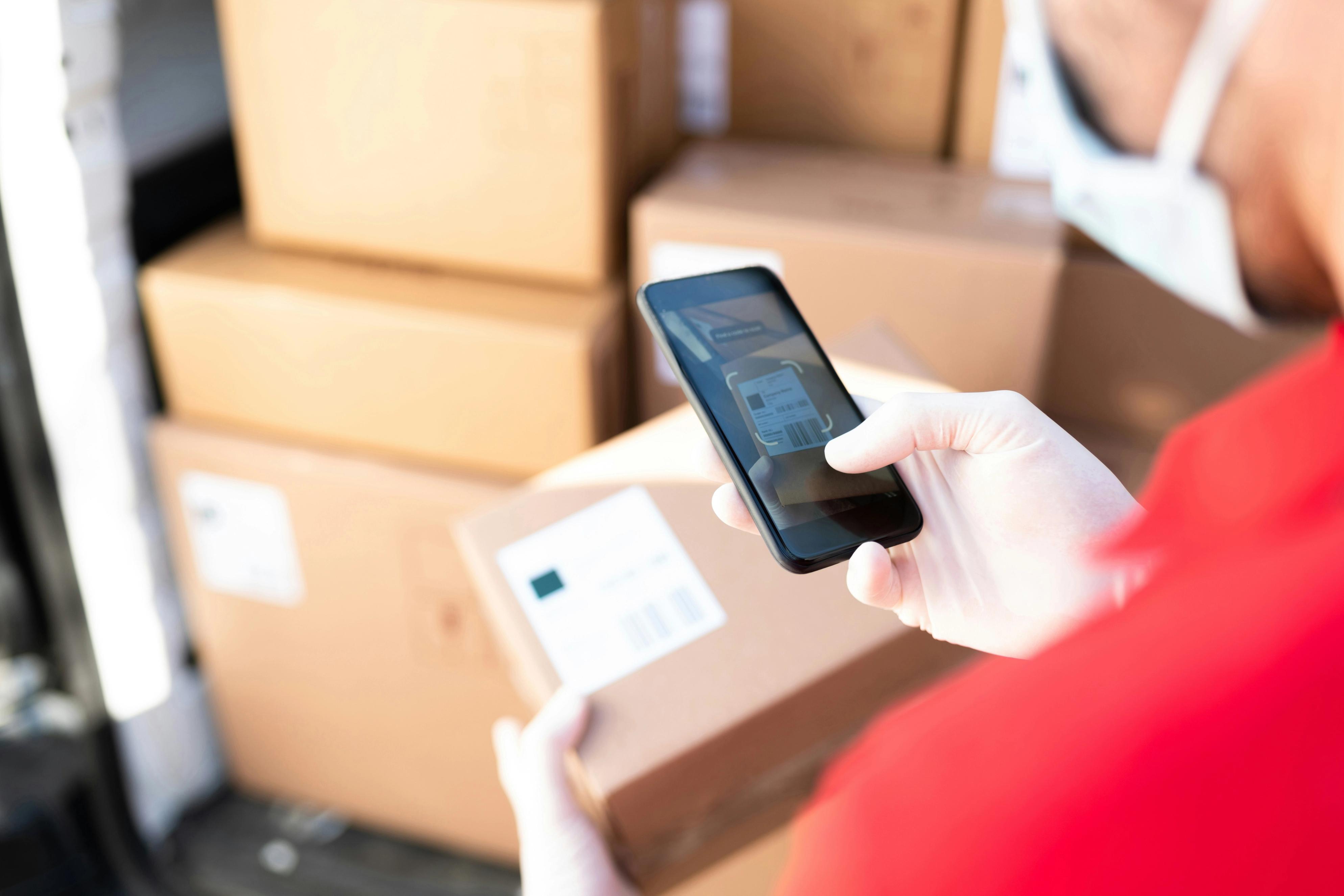 Dostavljač skenira oznaku na paketu pametnim telefonom