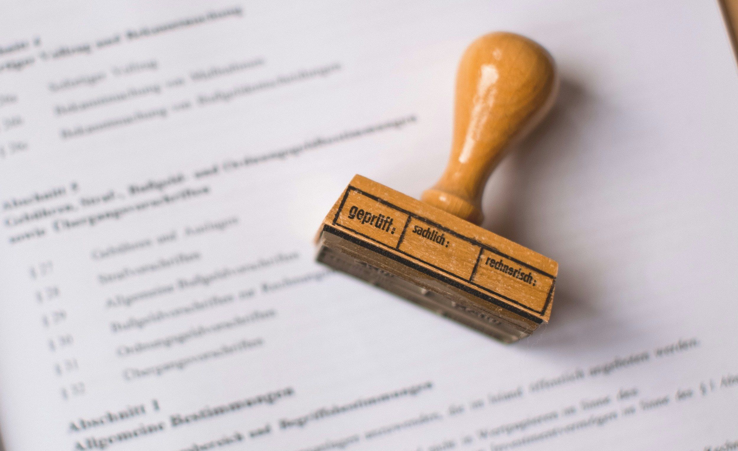 A wooden verification stamp resting on an open legal text.