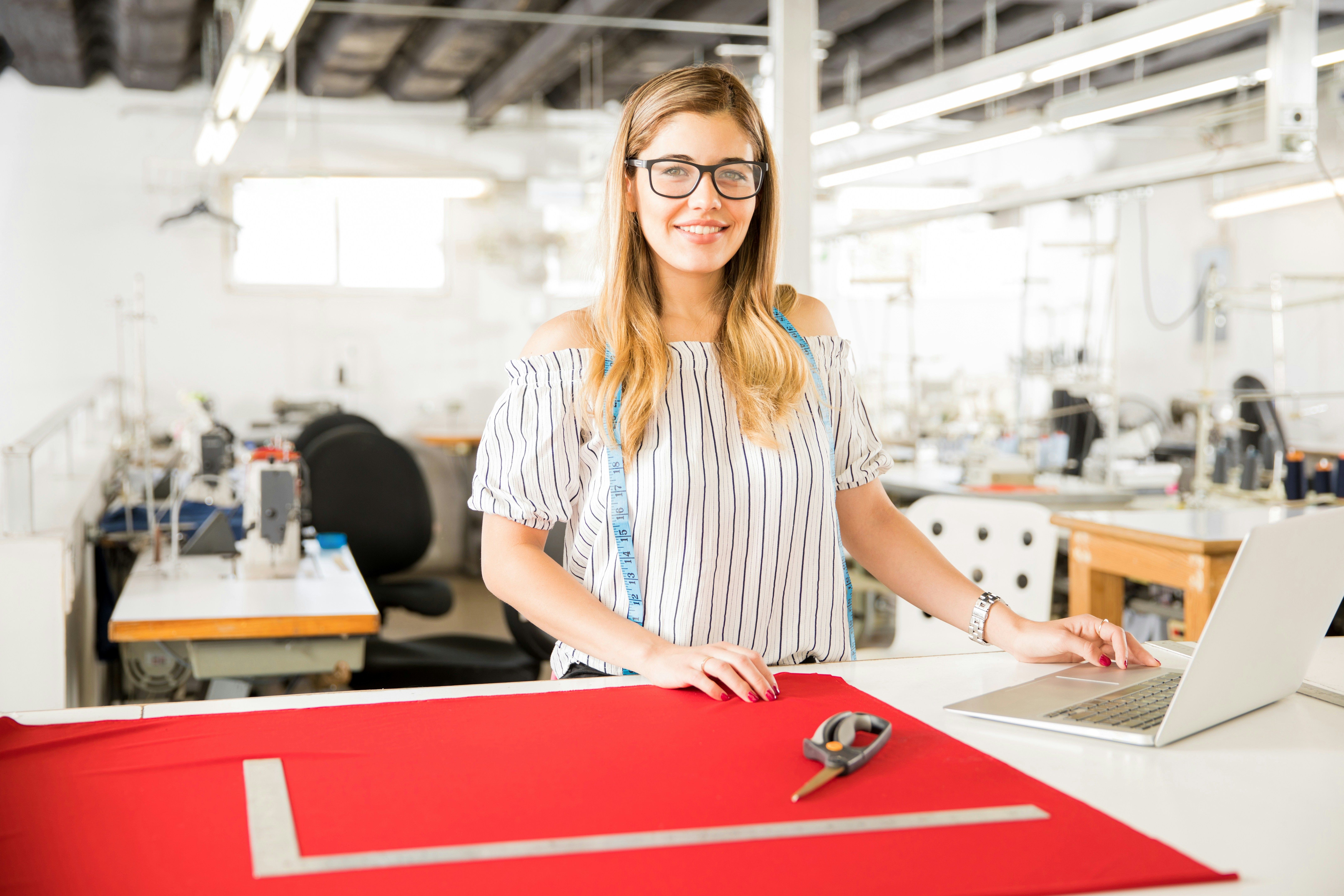 Designer in a textile studio using a laptop to track data and the Digital Product Passport (DPP).