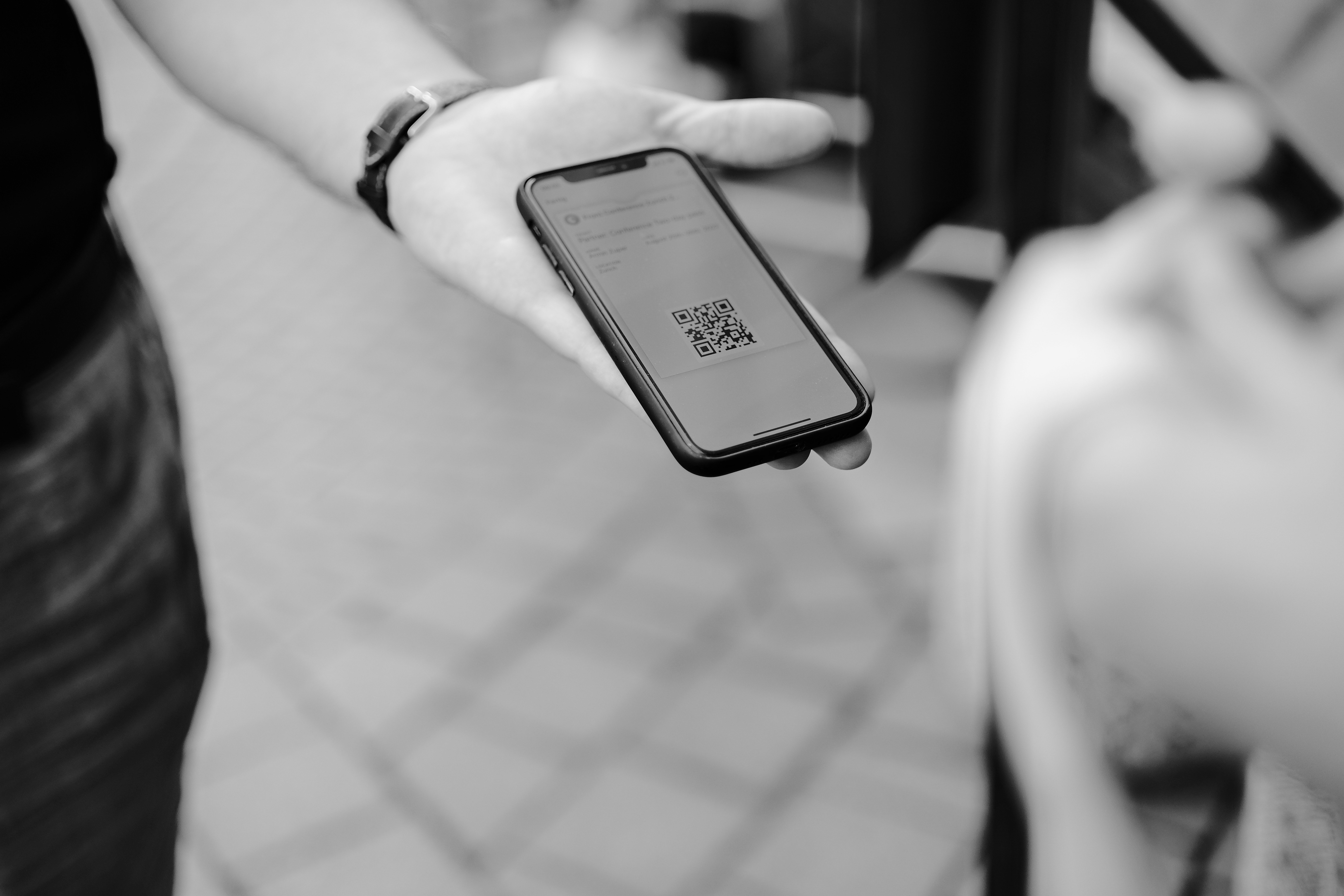 A hand holding a phone showing a QR code — scanning opens the passport, but does not prove the product is genuine.