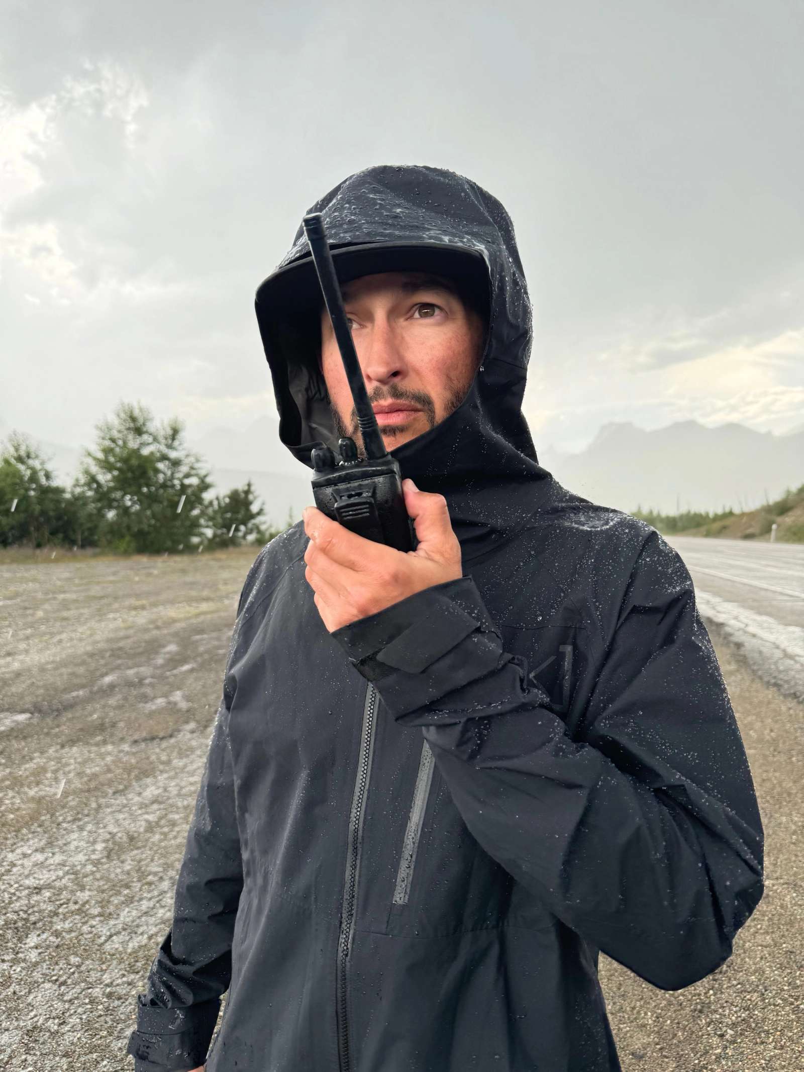 a man in a black jacket is standing on a walkie talkie.