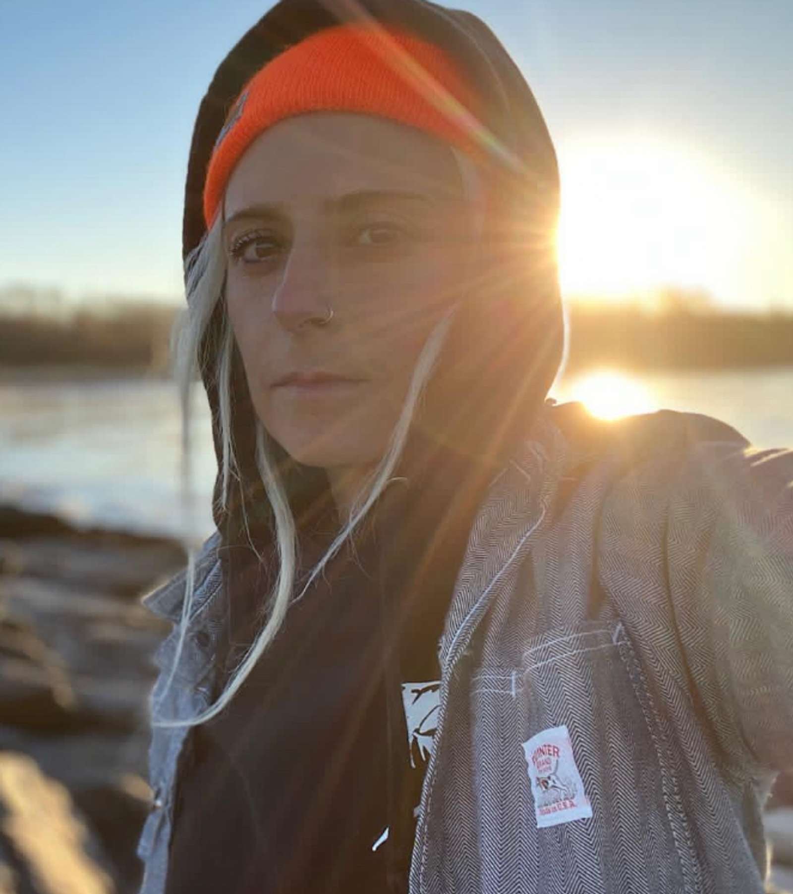 women with sun flare, bright orange beanie on