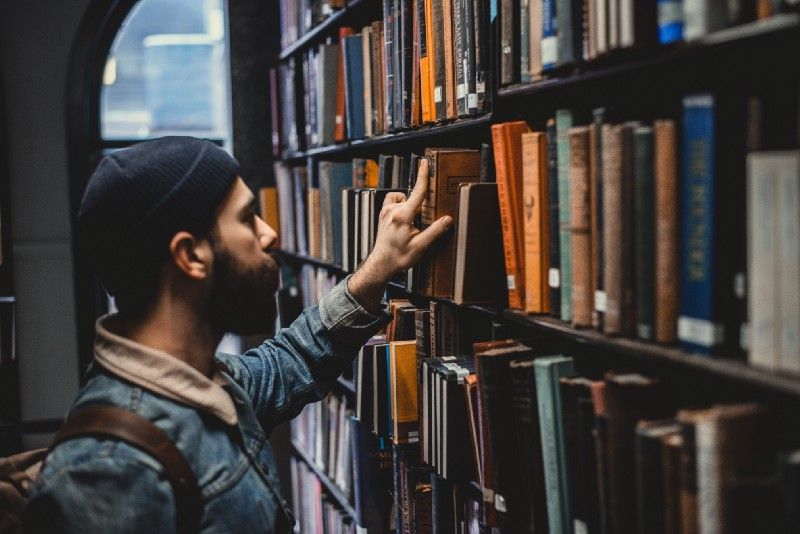 Person putting a book on a library shelf