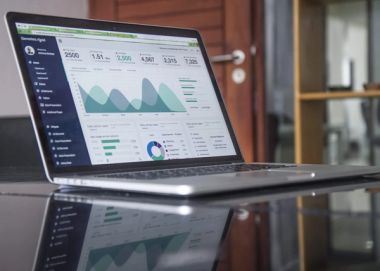 A laptop on a black table with analytics on screen