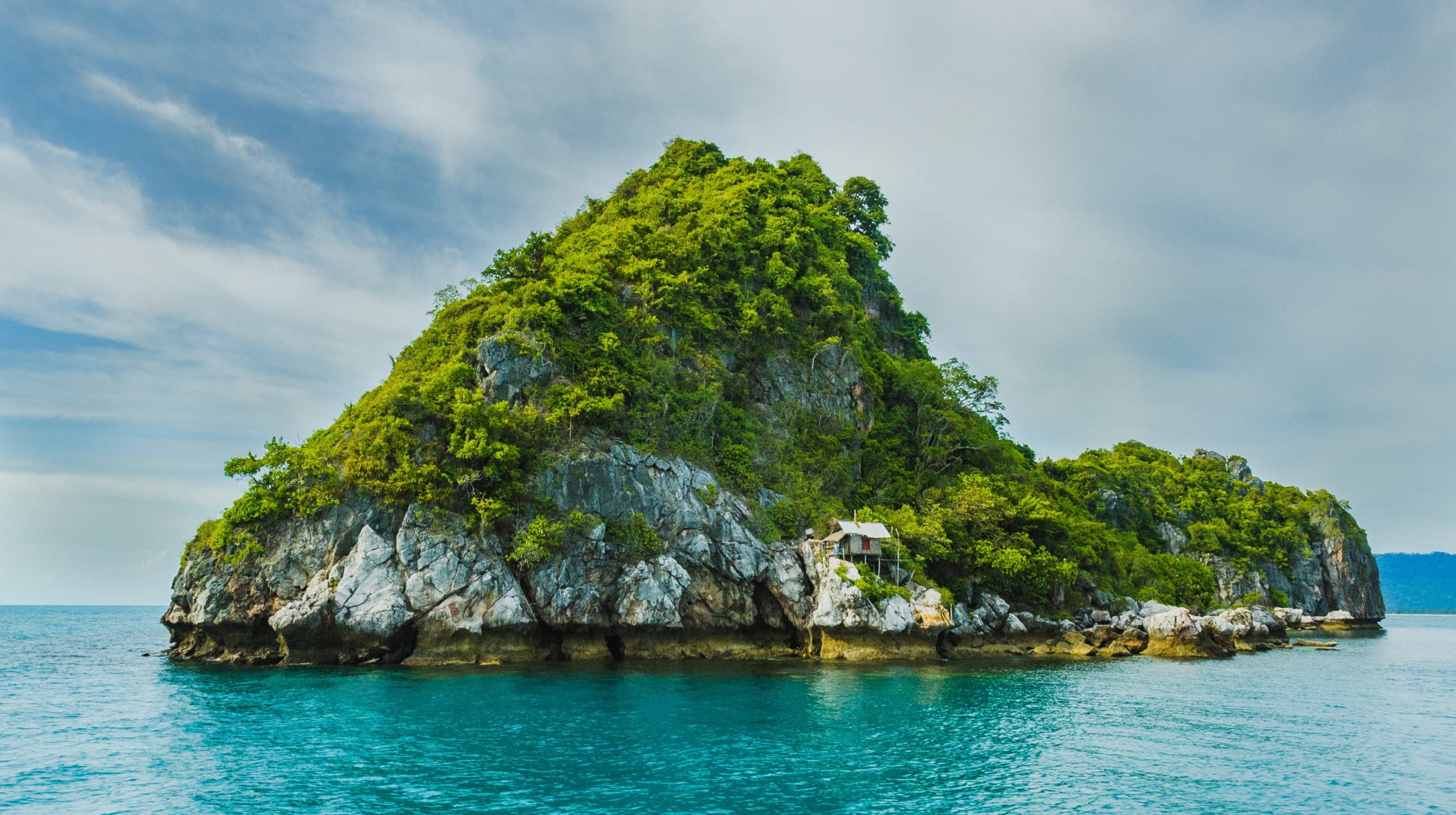 A very small island in a gulf with a small dwelling on the rocks