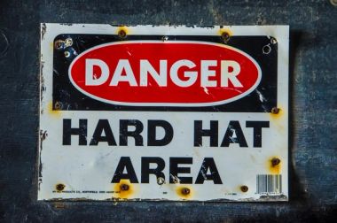 Old industrial warning sign that reads, Warning Hard hat area