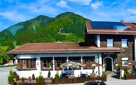 Außenansicht des Alpstuben mit Terrasse, dahinter der bewaldete Buchenberg