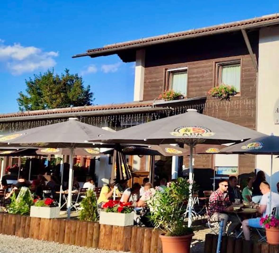 Gut besetzte Terrasse unter Sonnenschirmen an einem sonnigen Sommerabend