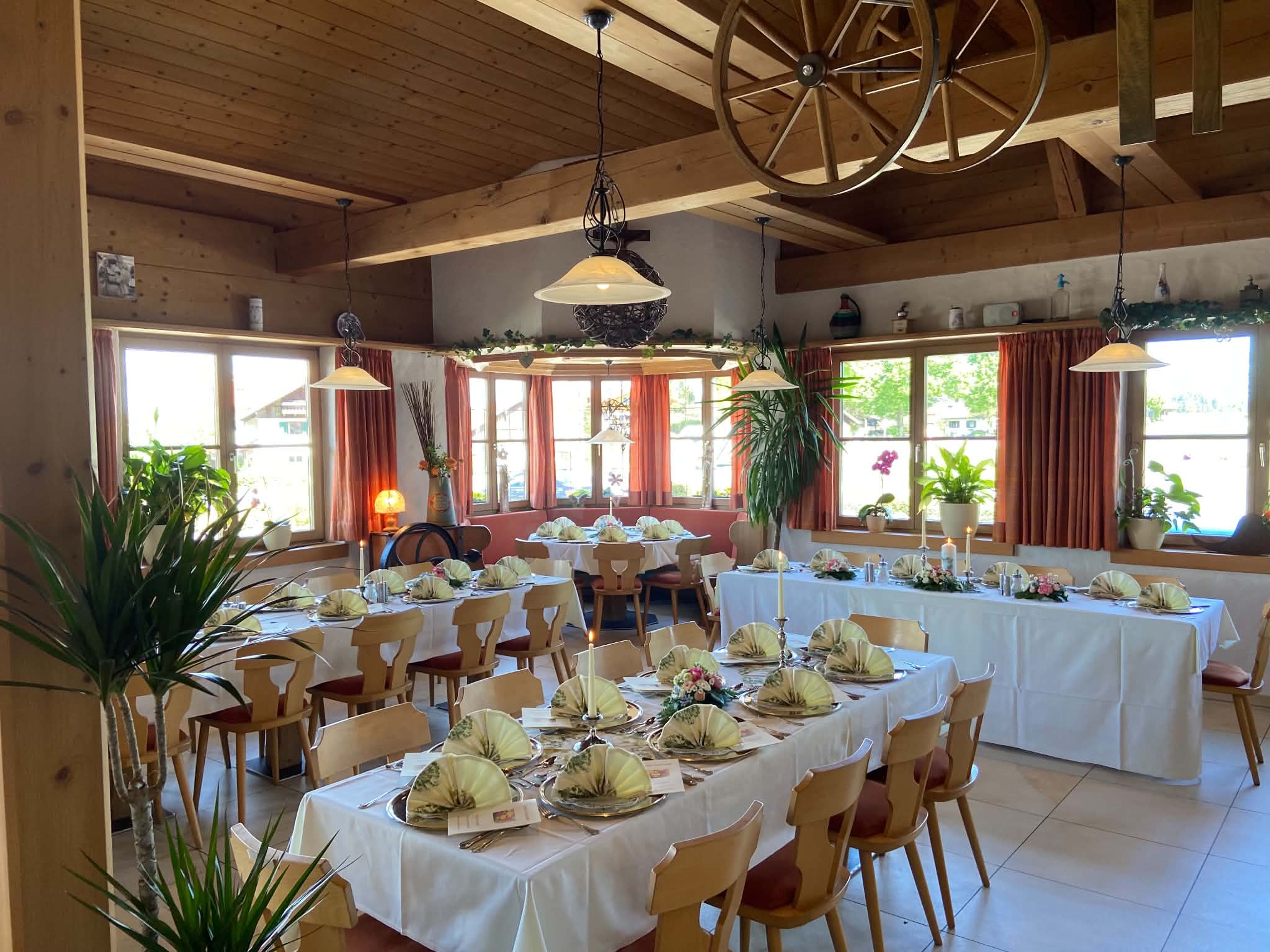 Festlich eingedeckte lange Tafeln mit weißen Tischdecken, Kerzen und Blumenschmuck