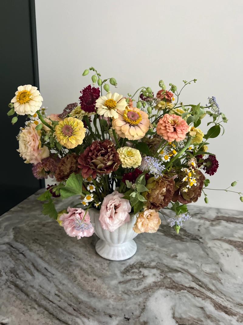 a lush bouquet of zinnias and other flowers on a stone counter