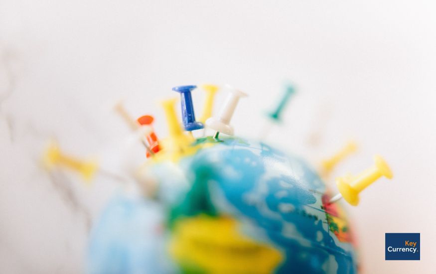 Different coloured pins pressed into a world globe showcasing different destinations around the world.