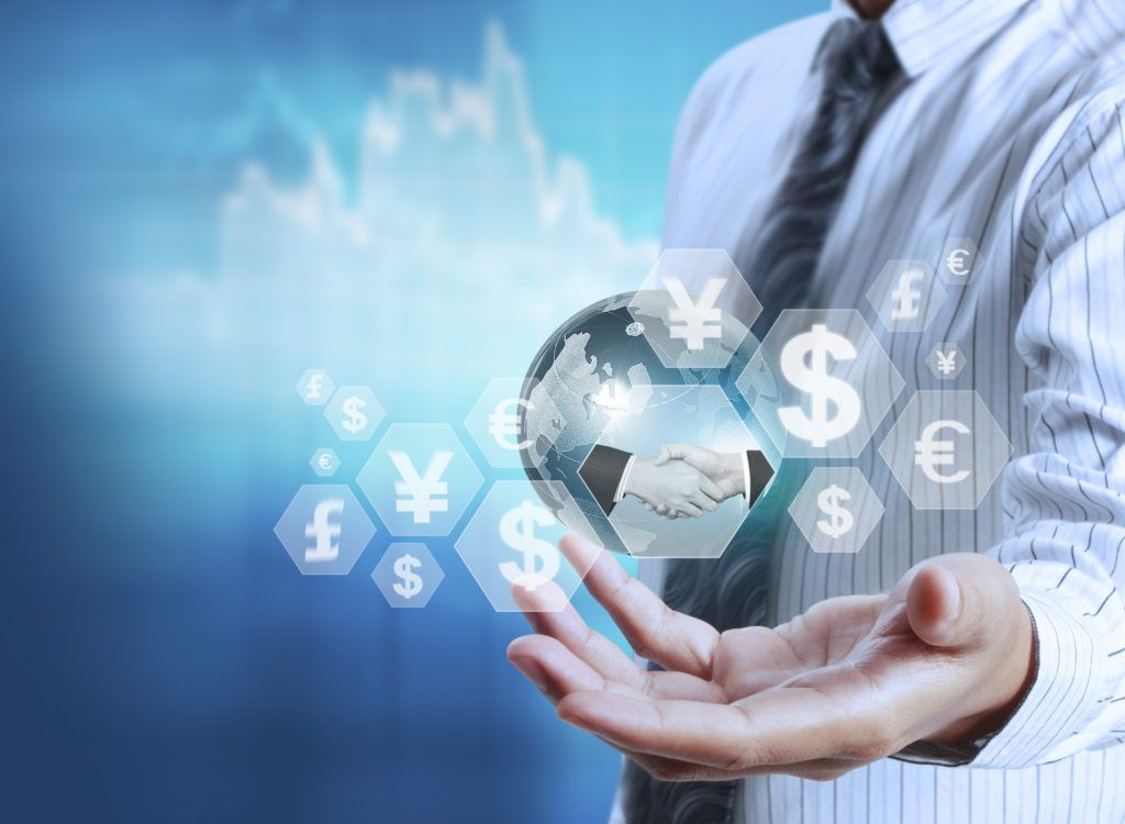 Image of a person holding a globe with various currency symbols floating around. Depicting international money transfers.