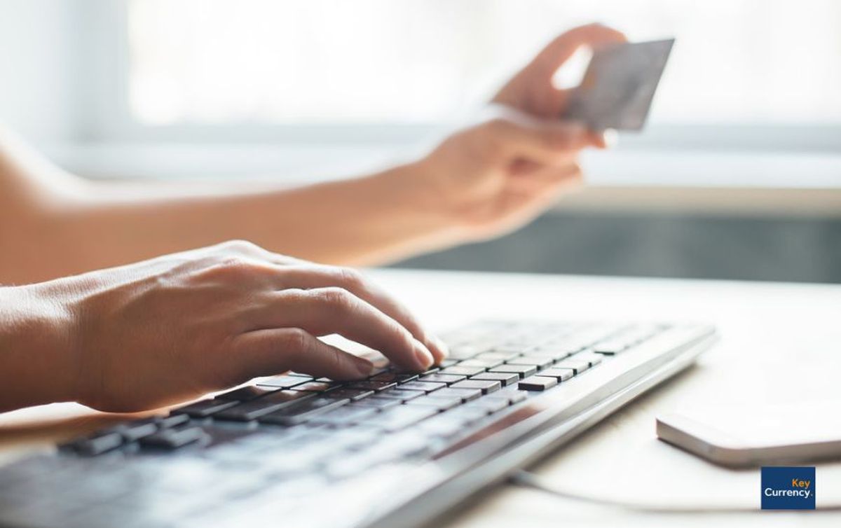 Person putting in bank details online using a computer. Person is also holding their bank card. 