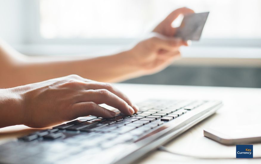 Person putting in bank details online using a computer. Person is also holding their bank card.