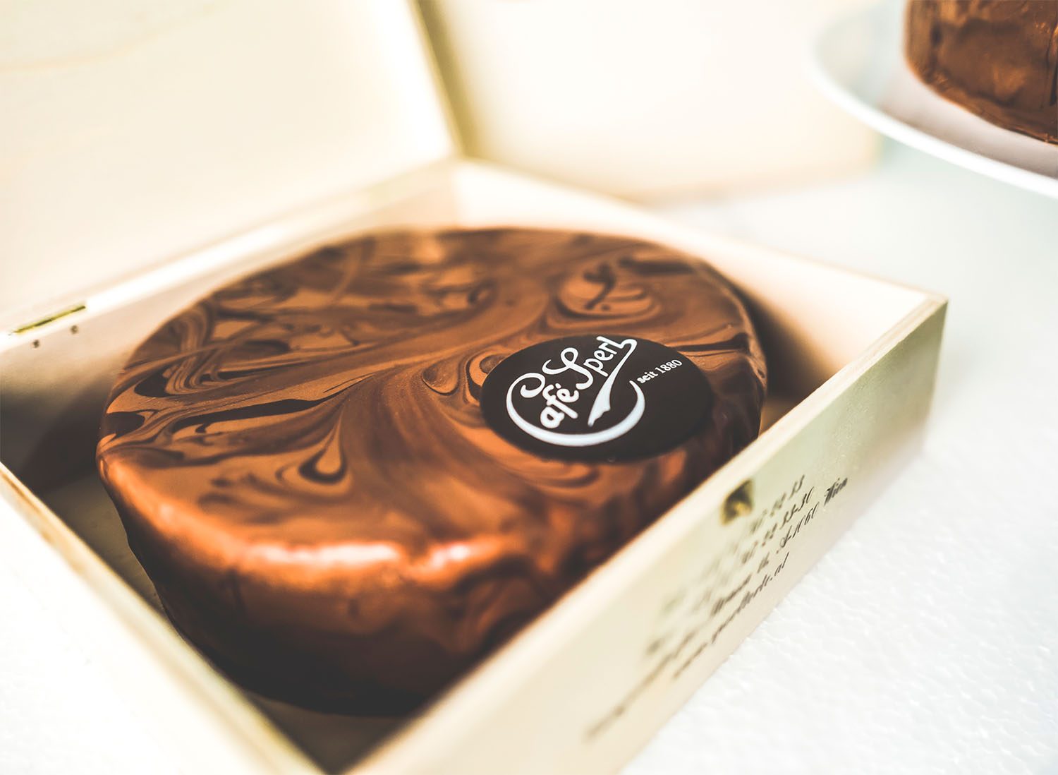 Original Sperl Torte im Holzkistchen mit einem servierten Stück