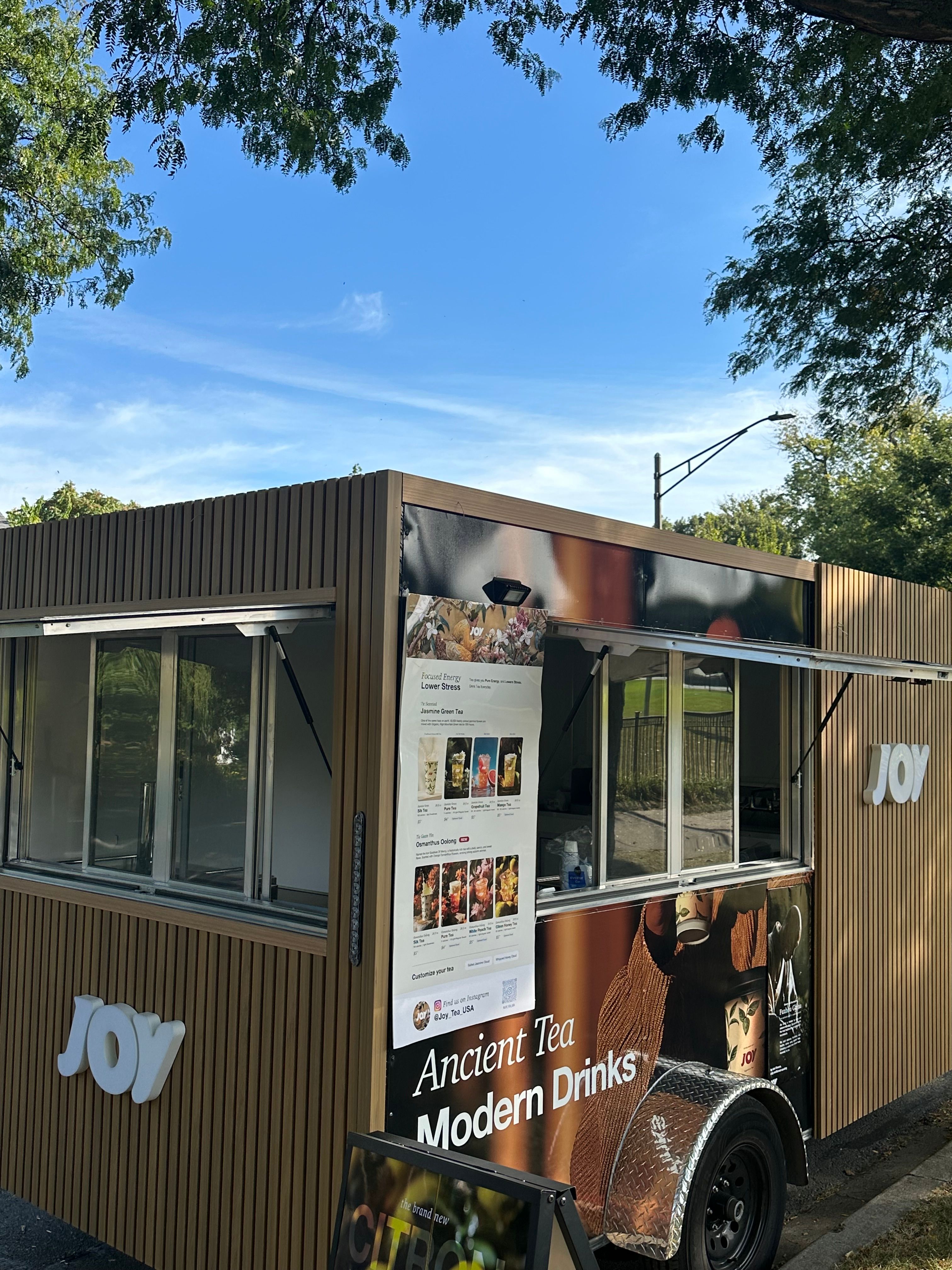 The Joy Tea trailer with its service windows open and an Ancient Tea, Modern Drinks banner