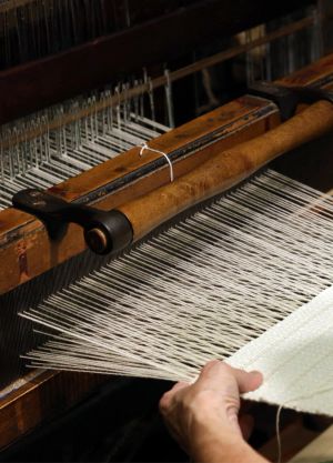 A white rug being woven at an antique loom