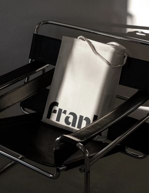 A tote bag with the Frank logo on a modern leather armchair