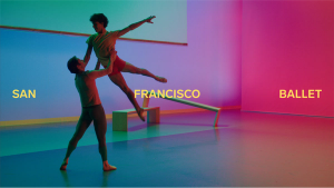 Two dancers in a colorfully-lit room with overlayed text reading "SAN FRANCISCO BALLET"