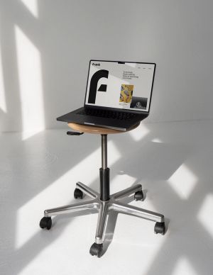 The Frank website on a laptop. The laptop sits on a rolling stool in a white room with natural light.