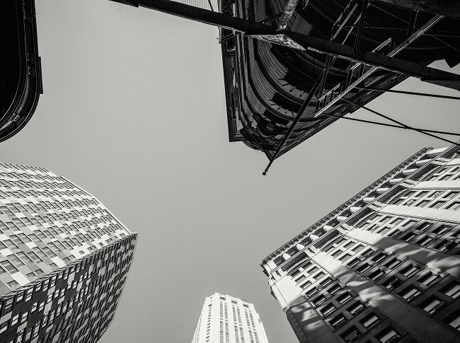 Vista en blanco y negro de rascacielos desde el suelo hacia el cielo, simbolizando crecimiento y oportunidades inmobiliarias con Bulldeq como tu aliado estratégico