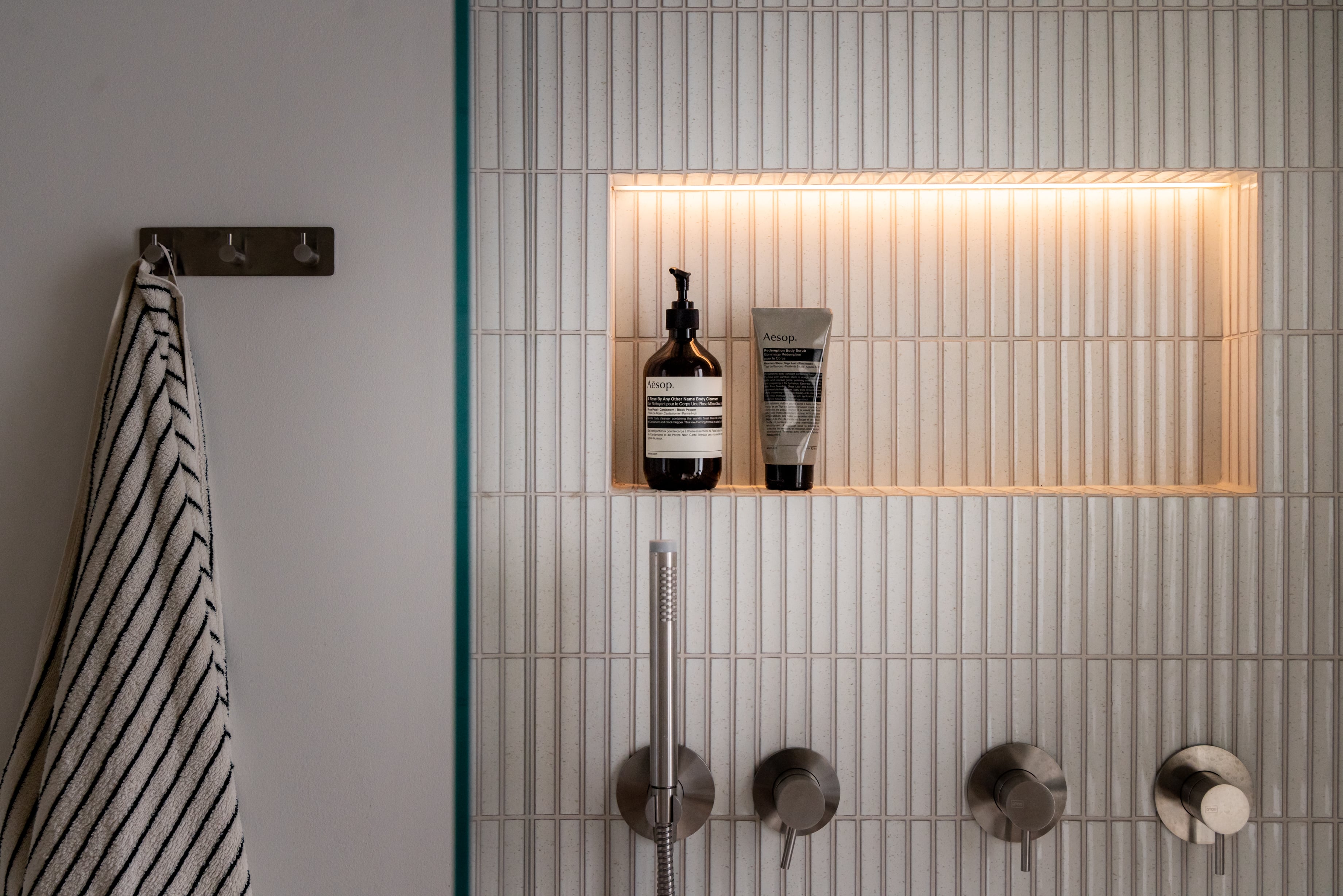 Bad med hvit kitkat flis, innebygd hyllenisje med led-stripe og innebygde armaturer. Badet er pusset opp av Lomundal.