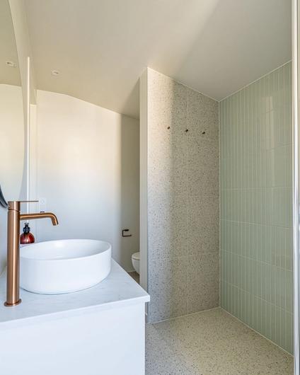 Baderom i lys, nordisk stil med en minimalistisk innredning med terrazzoflis på gulv og vegger, samt dekorflis i dusjsonen. Den blanke, mintgrønne flisen i dusjsonen skaper detaljer i rommet og et hint av farge og personlighet. Badet er totalrenovert av Lomundal.