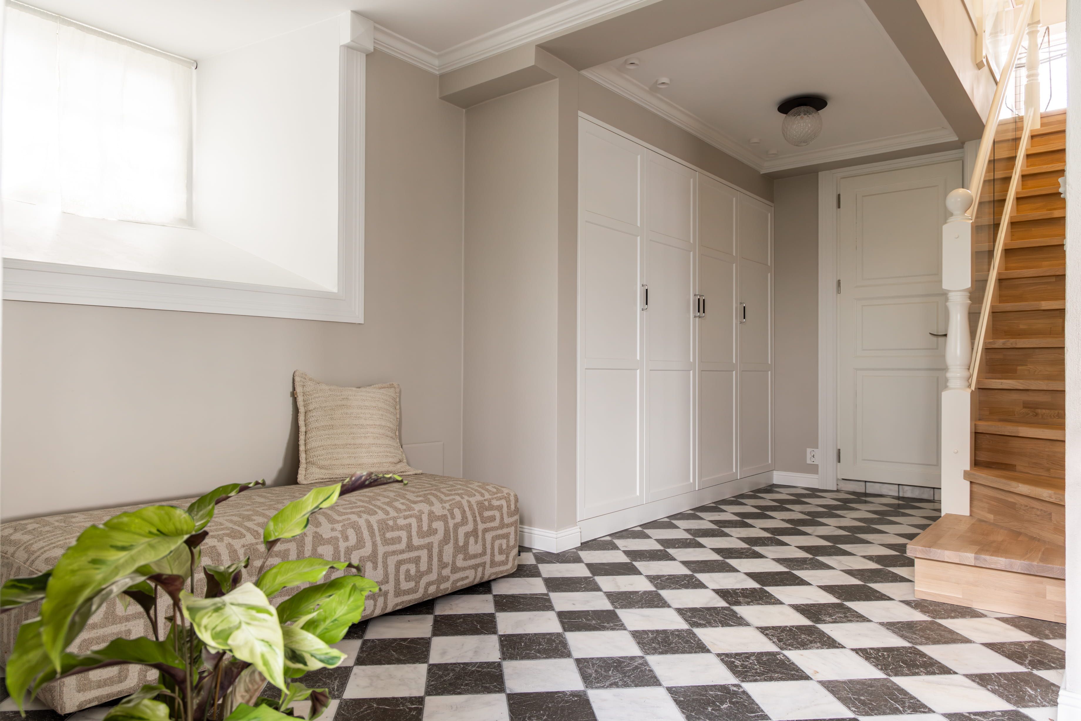 Entré i klassisk stil med gulvfliser i sjakkmønster, beige vegger og innebygd garderobe med elegant uttrykk. Utført av Lomundal.