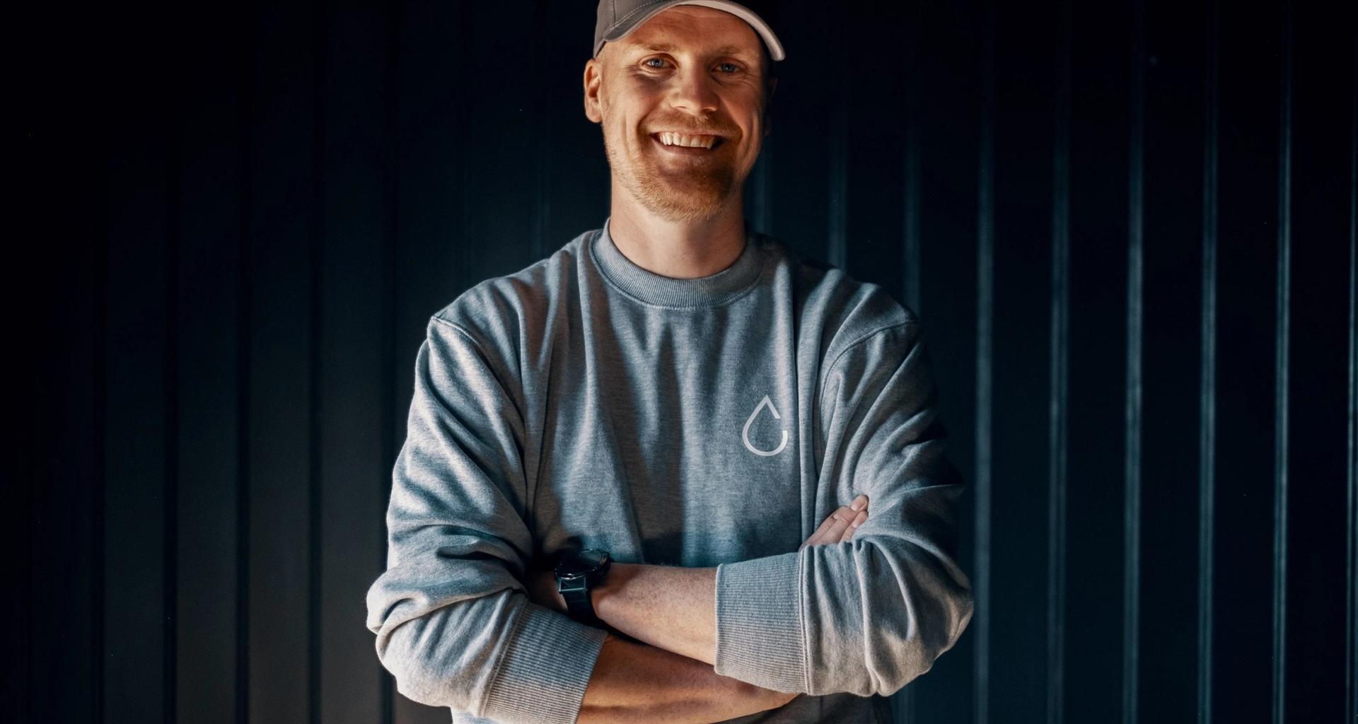 Simen står med armene i kors og smiler. Han er prosjektleder hos Lomundal.