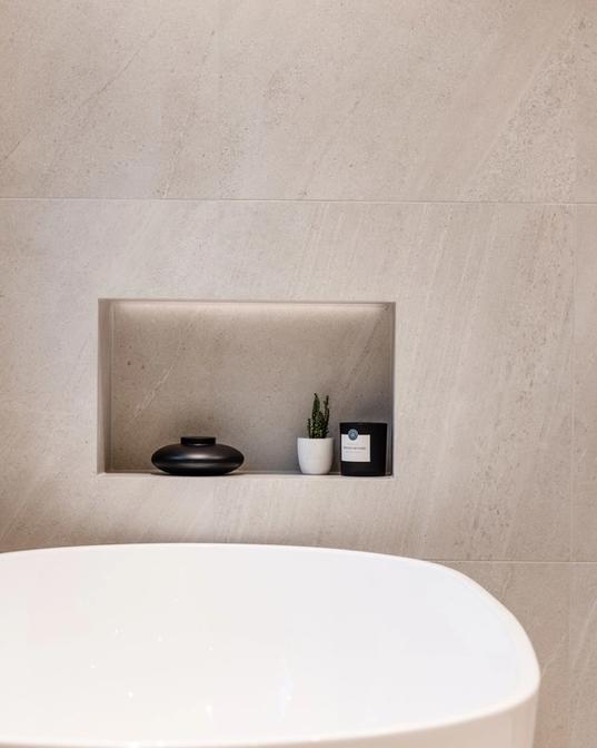 Detaljbilde av badekar med innebygd hyllenisje over med led-lyst i toppen. Utført av Lomundal.