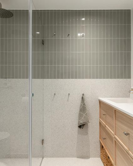 Totalrenovering av bad i skandinavisk stil med grønne, blanke fliser og terrazzofliser på vegg, samt gulv. Tidløs baderomsinnredning i lyst tre. Utført av Lomundal.