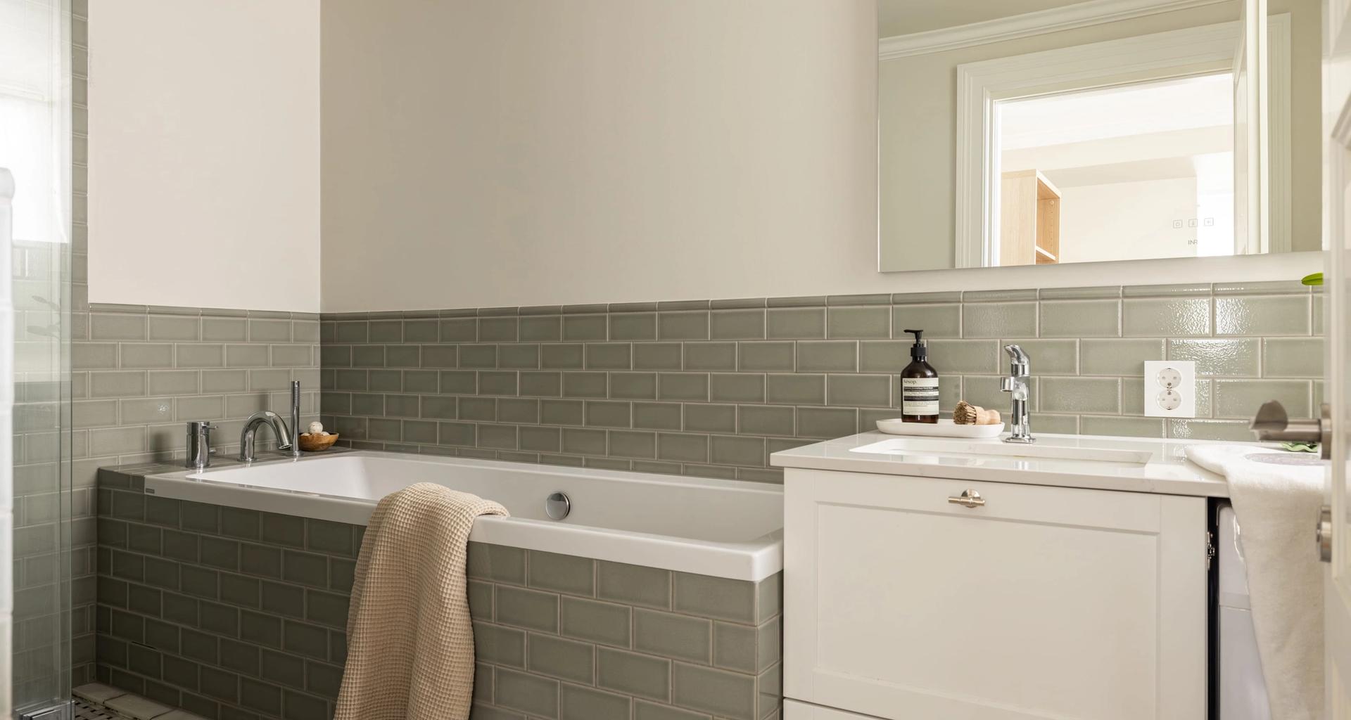 Klassisk bad med veggfliser i en dus grønntone. Badet har et tidløst uttrykk med en elegant kombinasjon av materialer og mønstre. Utført av Lomundal.
