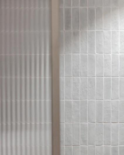 Et moderne bad med mosaikkfliser i en dus grønntone på vegg og dusjvegg i glass med rillet effekt. Utført av Lomundal.
