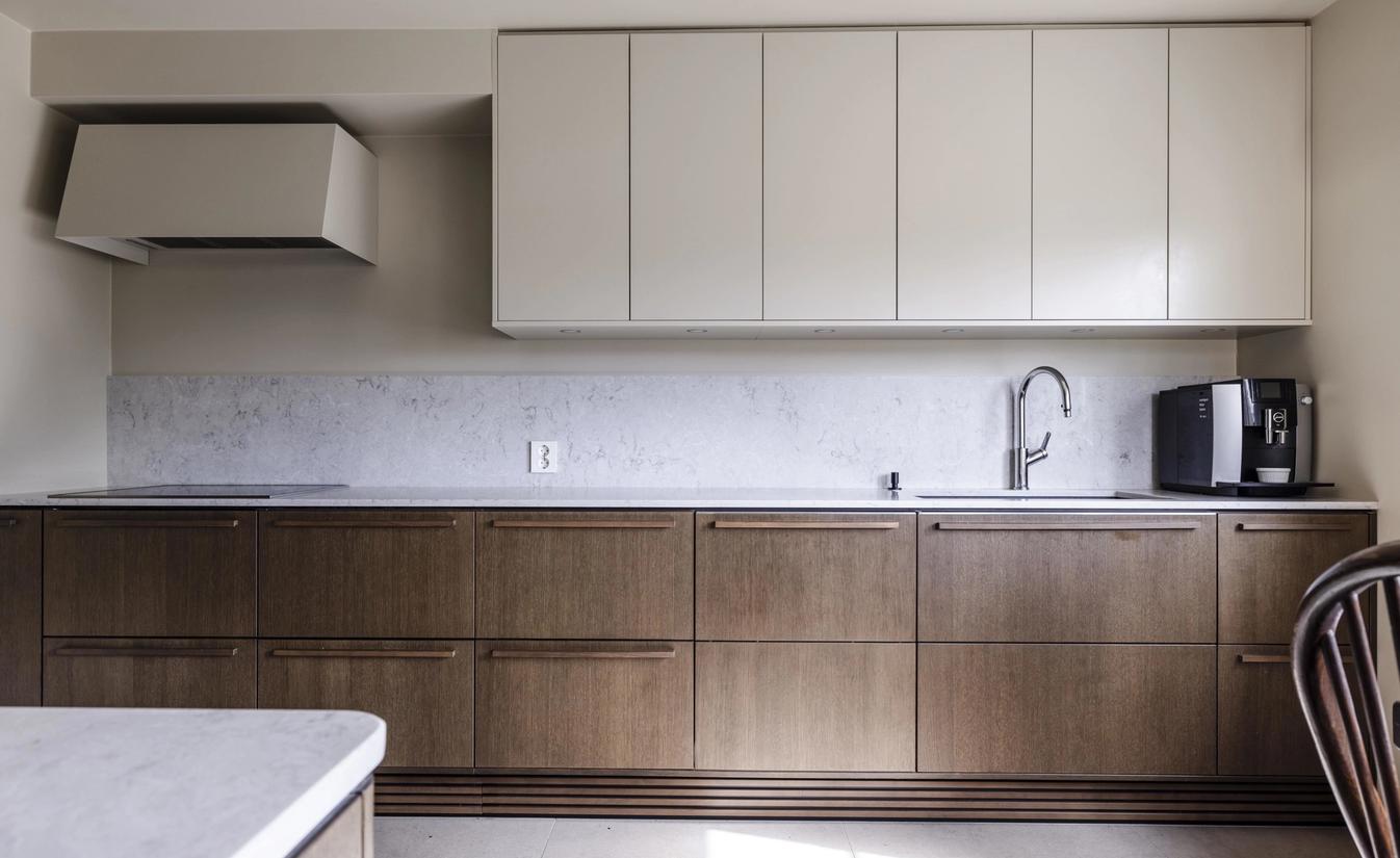 Kjøkkeninnredning i valnøtt fra Sigdal med overskap malt i samme beige tone som veggen. Benkeplate i lys sten. Pusset opp av Lomundal.
